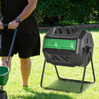 Black rotating dual-chamber composter with green front doors on outdoor grass