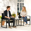Rattan bistro set with two dark wicker chairs, tan cushions, and a square glass-top table