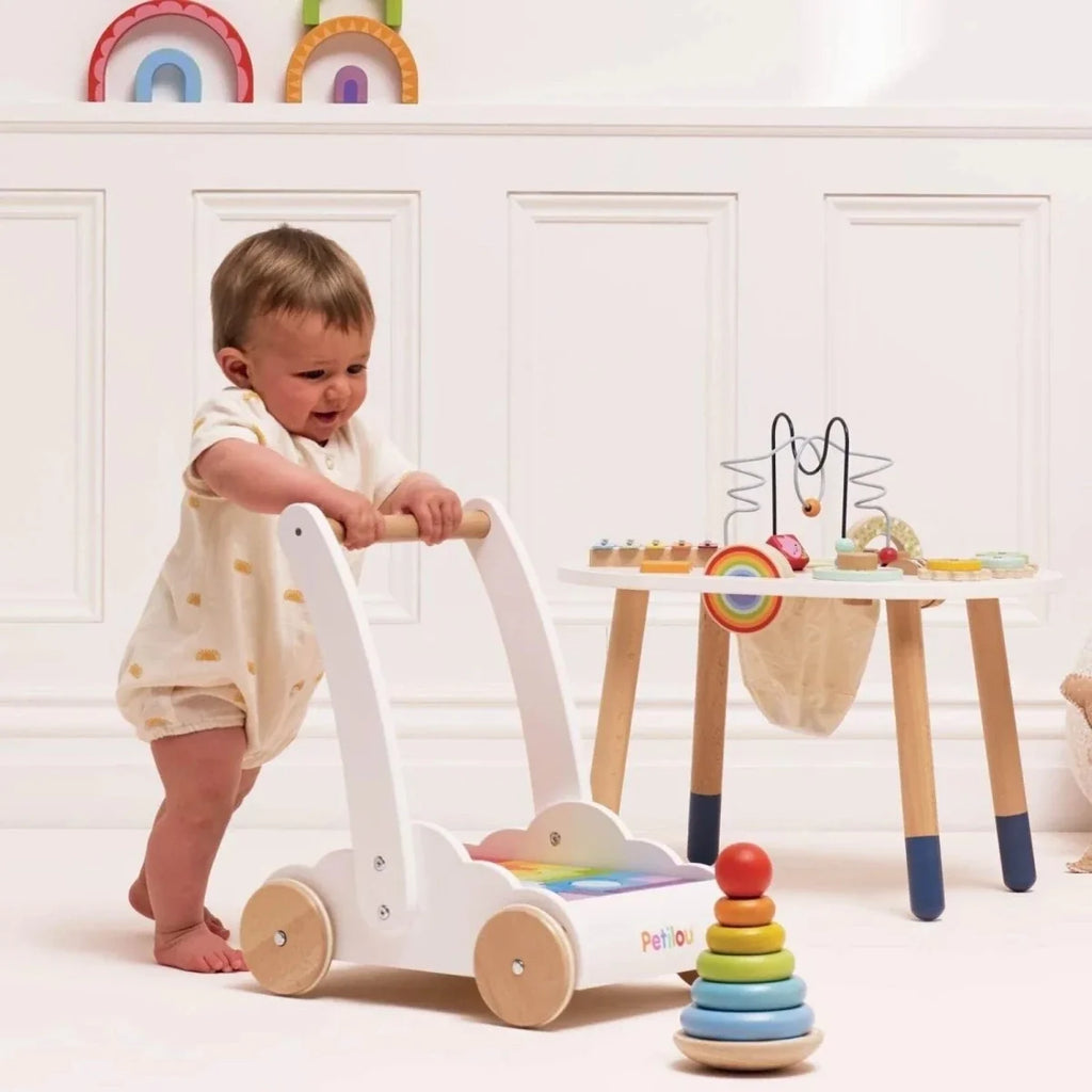 Rainbow block walker with wooden wheels, multicolored blocks, and a child playing