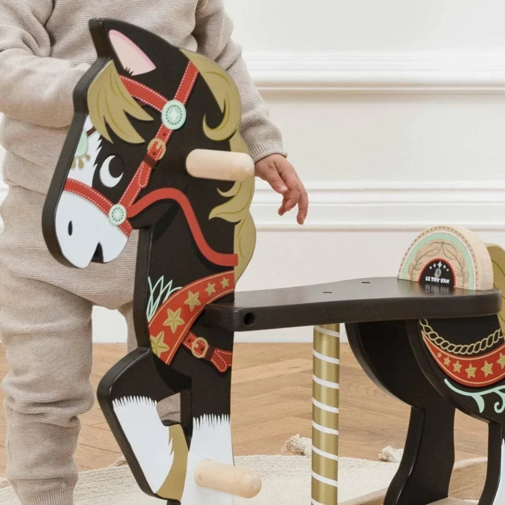Close-up of painted wooden rocking horse with red harness and white-and-cream face