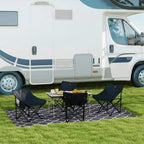 Black folding camping chairs with low metal legs and padded seats on outdoor mat