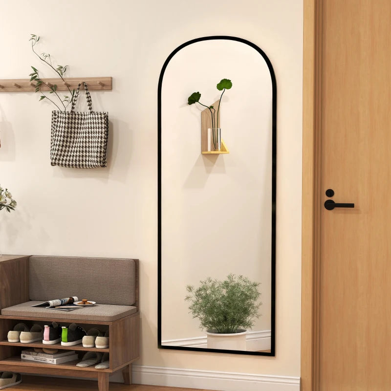 Black arched full-length standing mirror mounted upright against a wall
