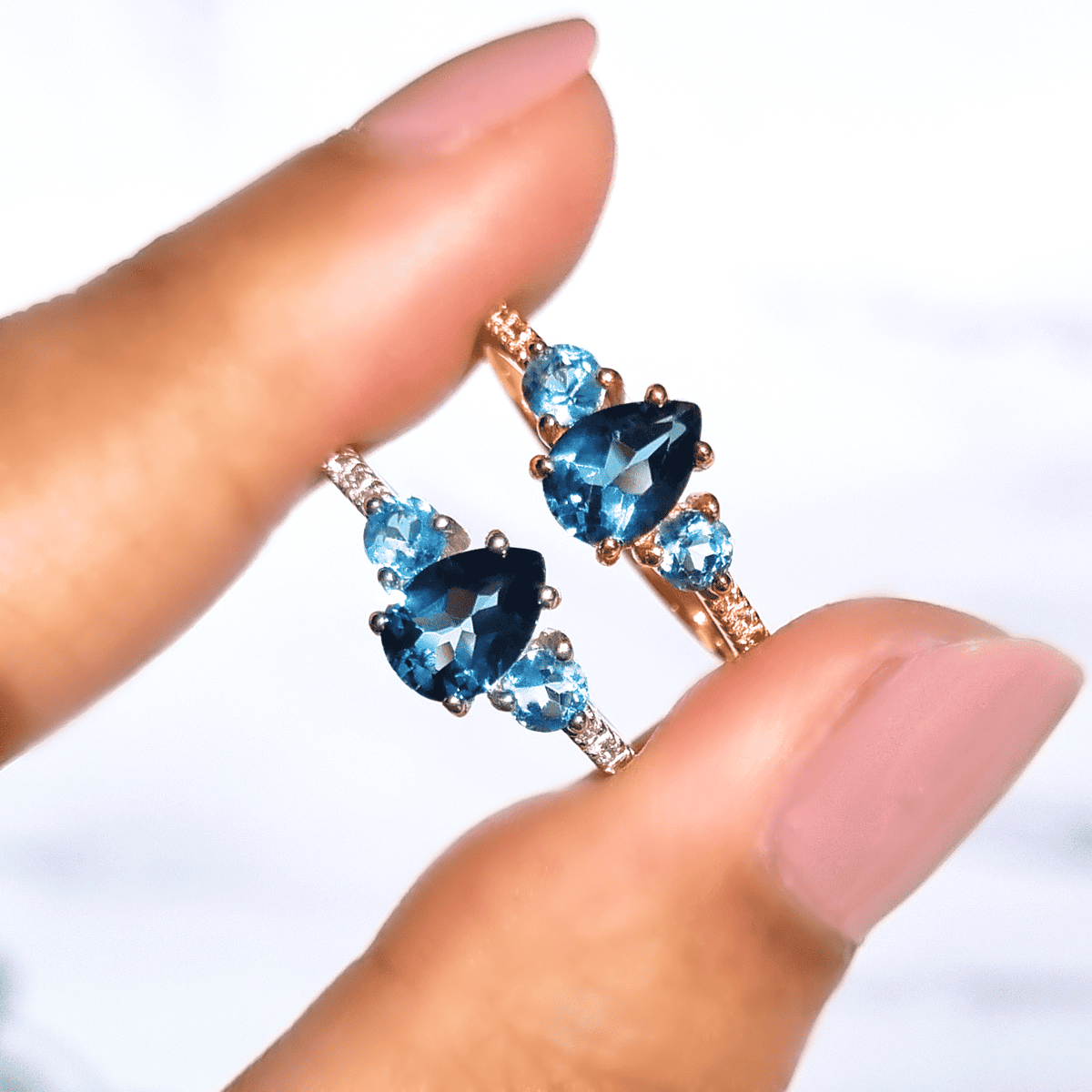 Rose-gold blue gemstone ring with oval center and round accents on fingers