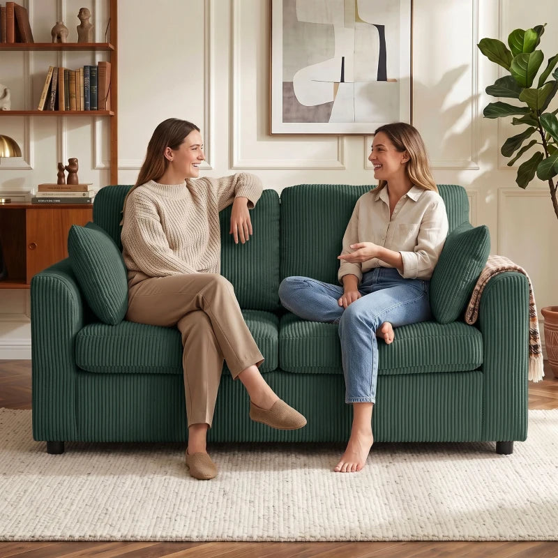 Dark green corduroy 2-seat sofa with two pillows, two people chatting while seated