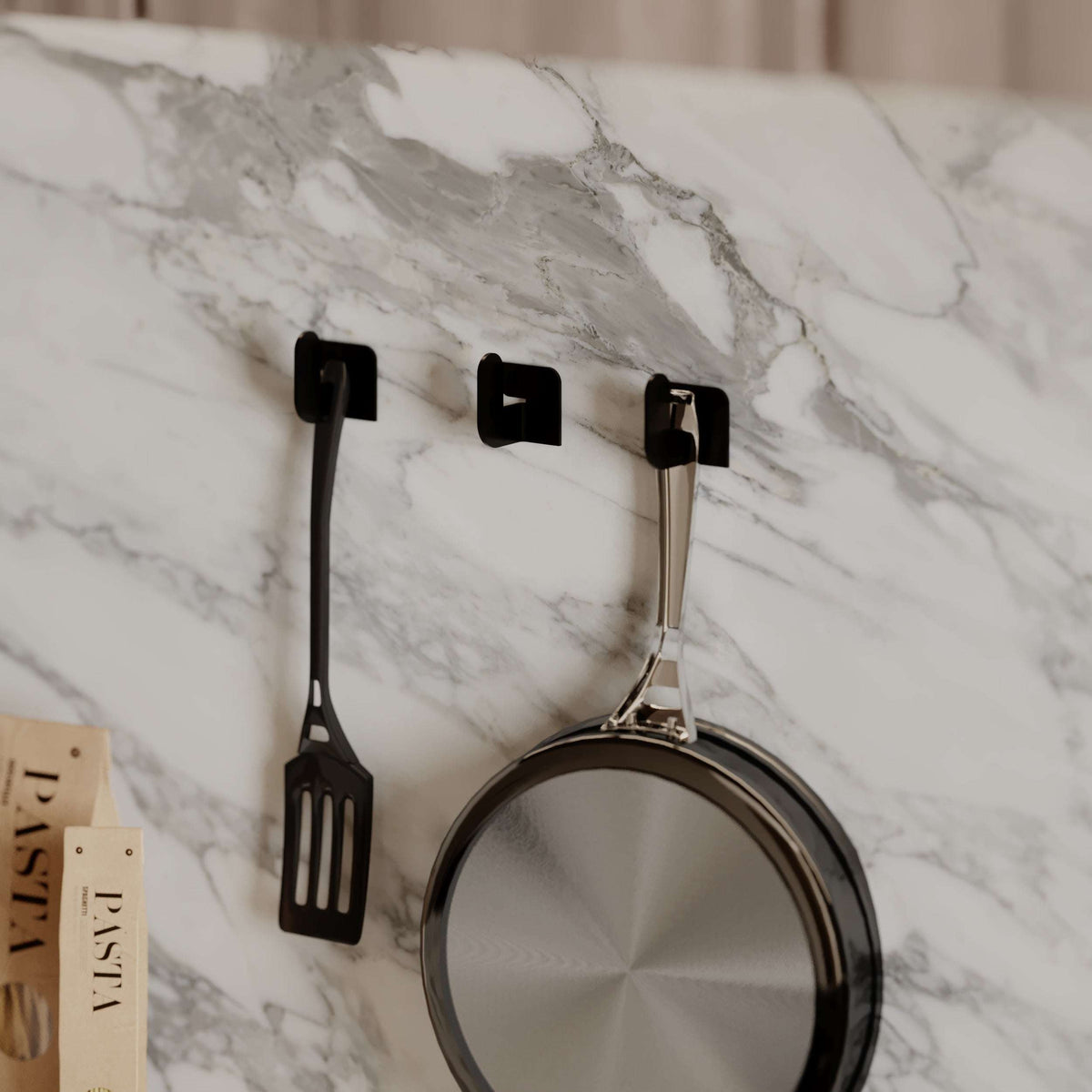 Wall-mounted black metal hooks with hanging kitchen utensils, three-piece set