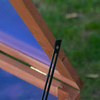 Close-up of hinged support rod holding the open top of a wooden cold frame