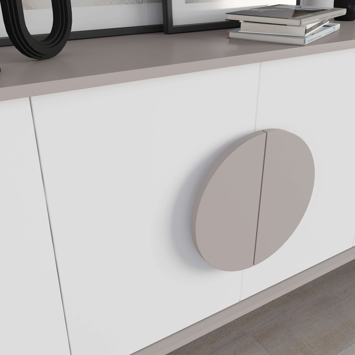 Close-up of white cabinet door with large taupe round handle and vertical seam