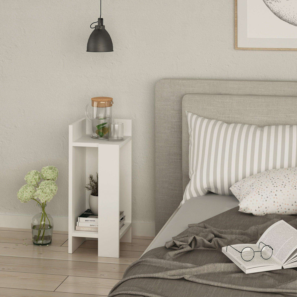 White narrow bedside table left module beside bed, with open shelving for small items