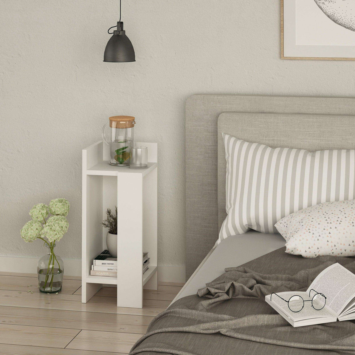 White narrow bedside table left module beside bed, with open shelving for small items