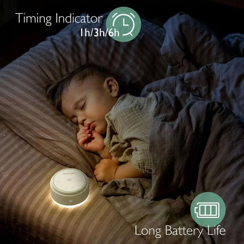White Momcozy white noise machine on a bedside surface, with power button visible