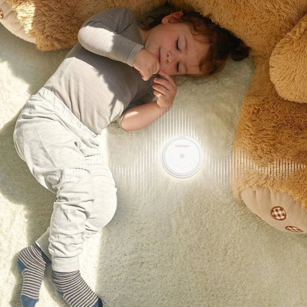Top view of Momcozy white noise machine on a rug, circular mint control display