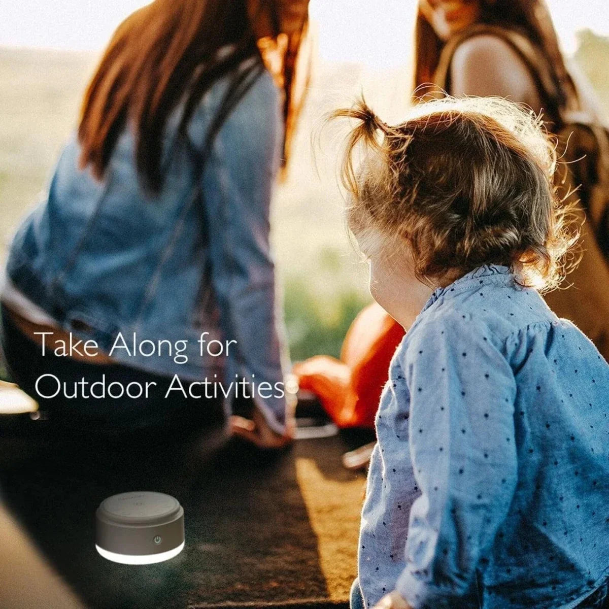 Portable white Momcozy white noise machine on the ground, round body and top controls