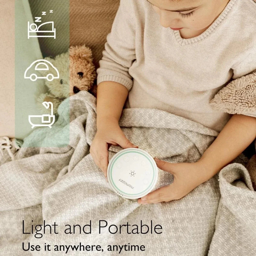 Momcozy white noise machine held in hand, round mint control top and white base
