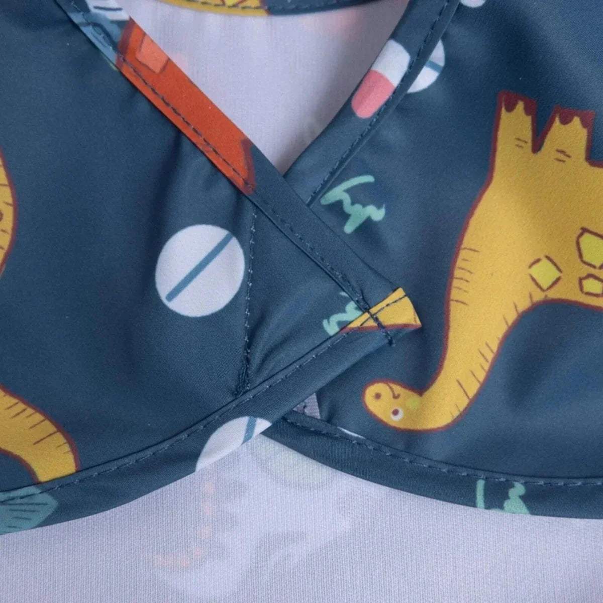 Blue baby bib neckline detail with stitched trim and dinosaur print pattern