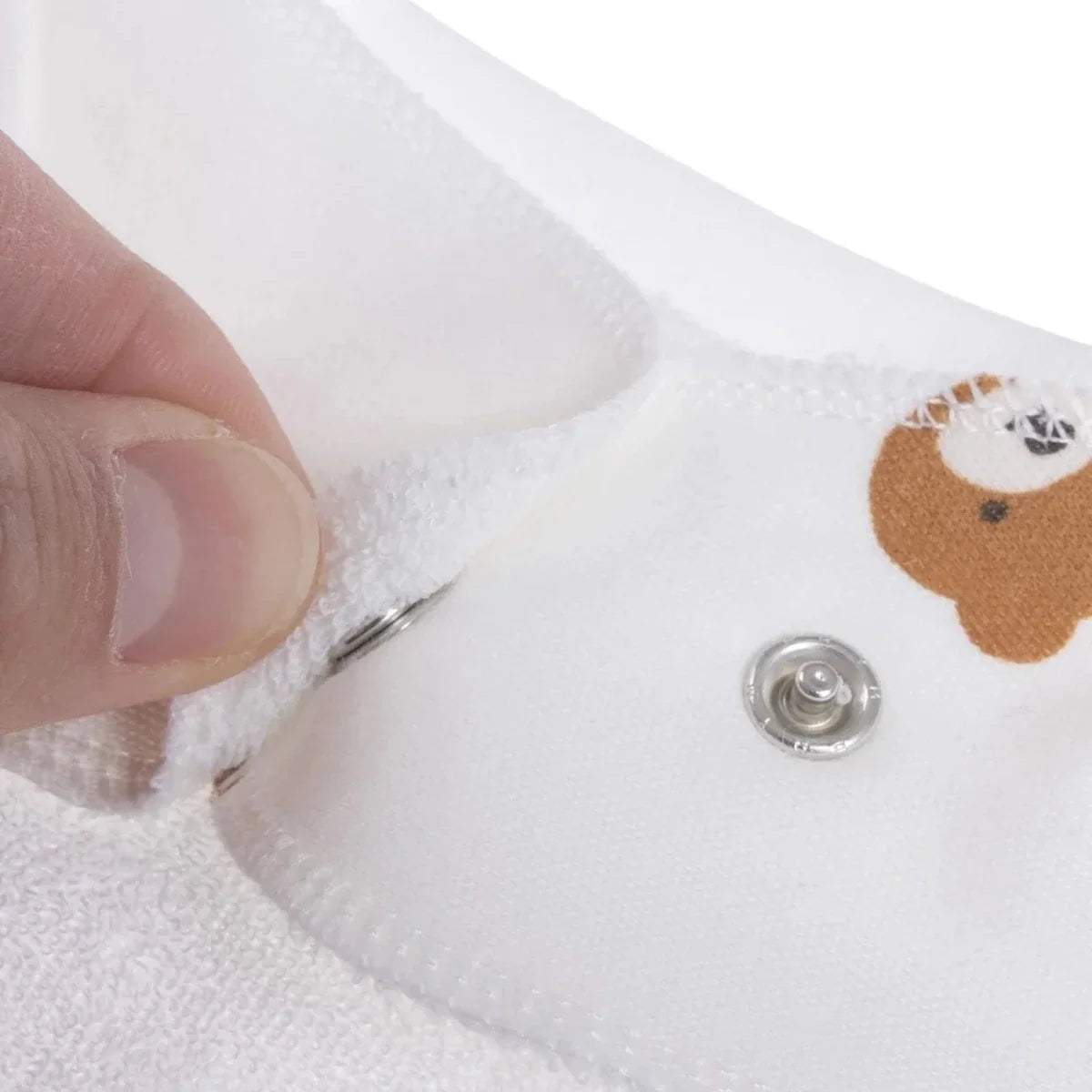 Close-up of white cotton bandana bib snap button and teddy print fabric edge