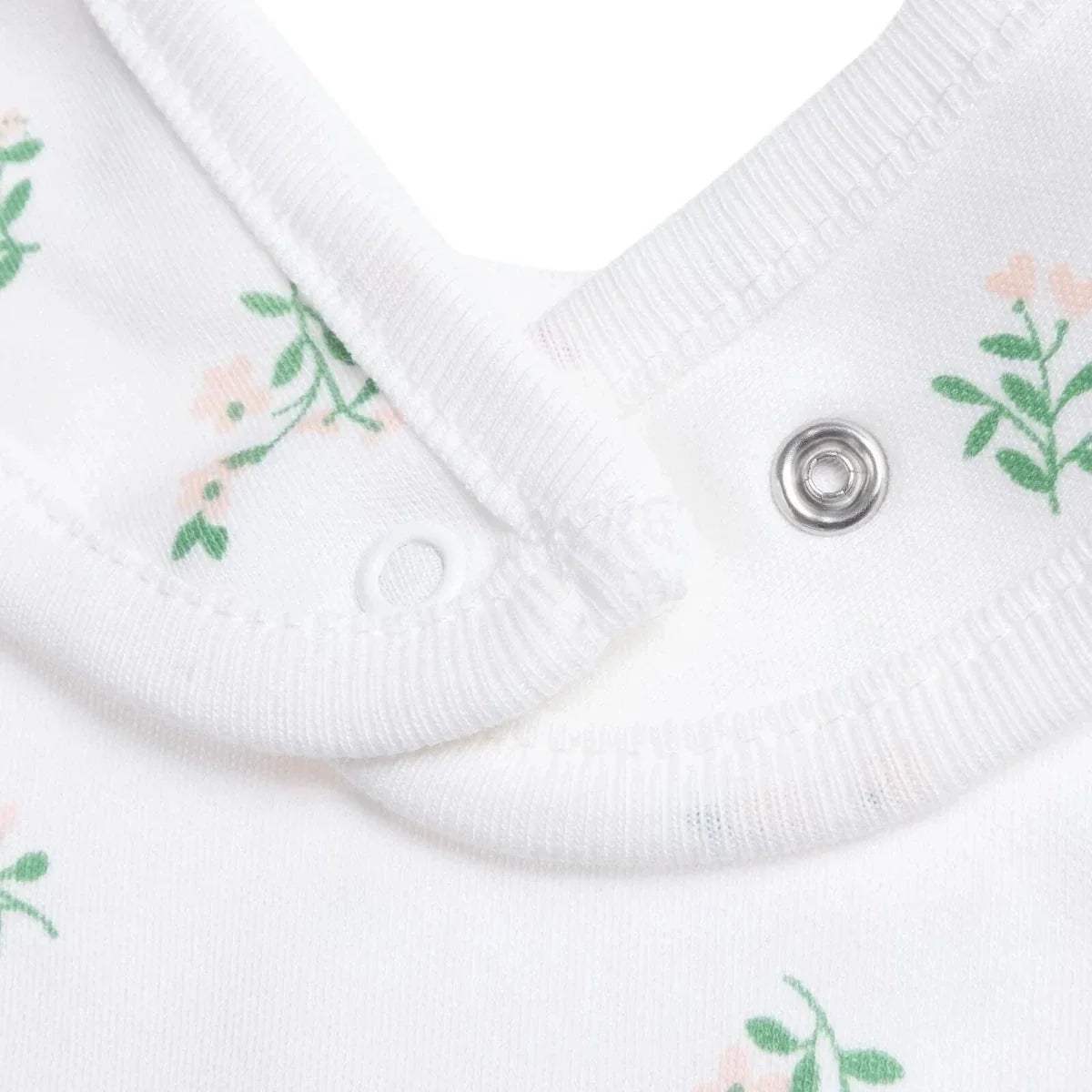 White baby bib neckline with metal snap and small green floral print on fabric.