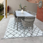 Gray and white trellis-pattern outdoor rug laid under a patio dining table
