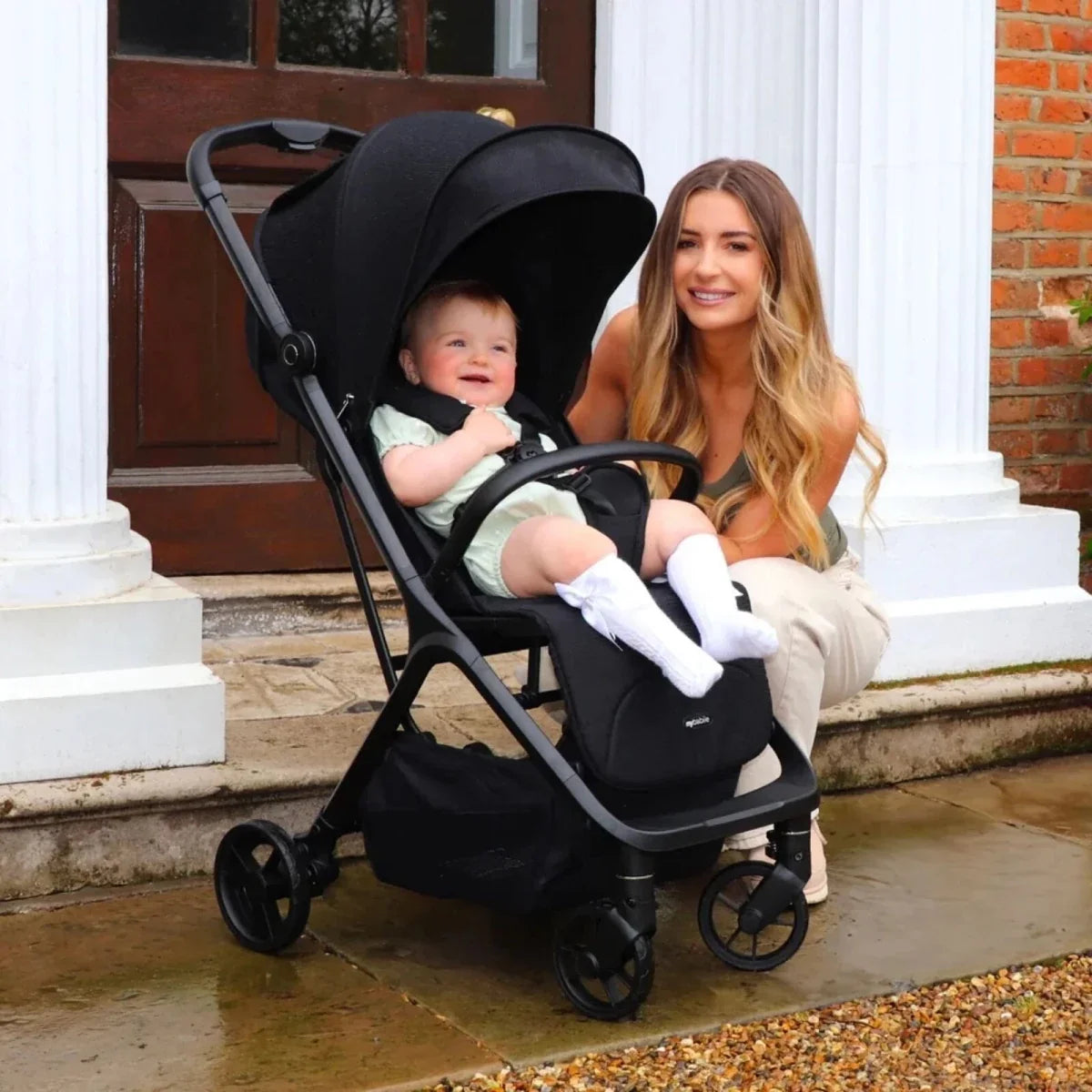Compact stroller with toddler seat and canopy, shown with caregiver on steps outdoors