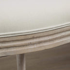 Close-up of cream fabric cushion edge on distressed light-wood dining chair