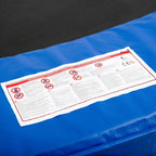 Blue trampoline pad with white safety label on textured foam surface