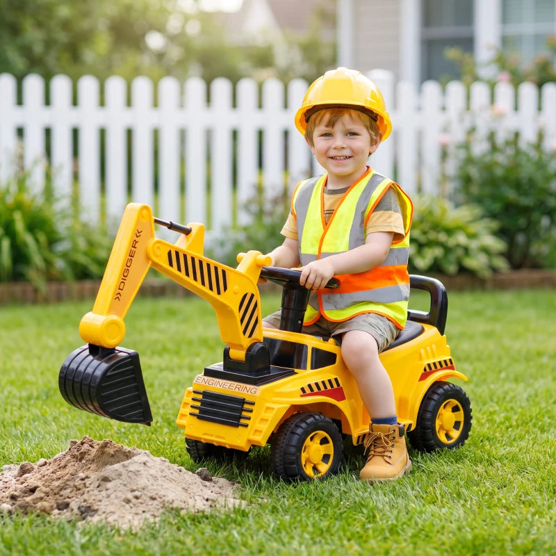 Yellow kids ride-on digger toy with front scoop digging into sand; child seated wearing helmet