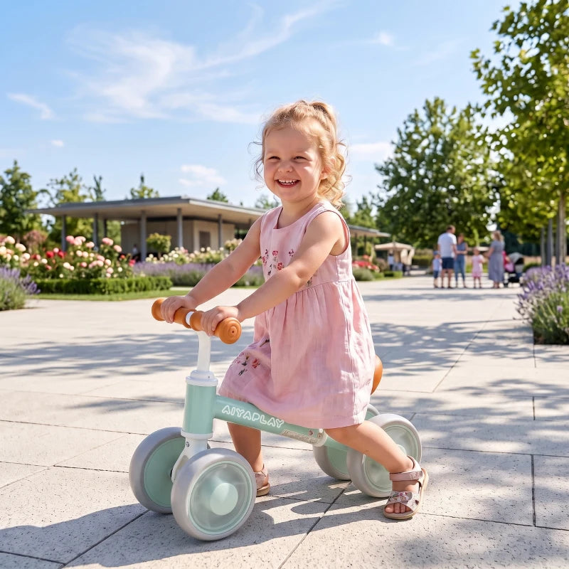 Green balance bike with orange seat and glowing wheels, toddler riding outdoors