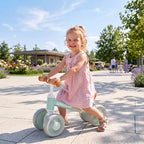 Green balance bike with orange seat and glowing wheels, toddler riding outdoors