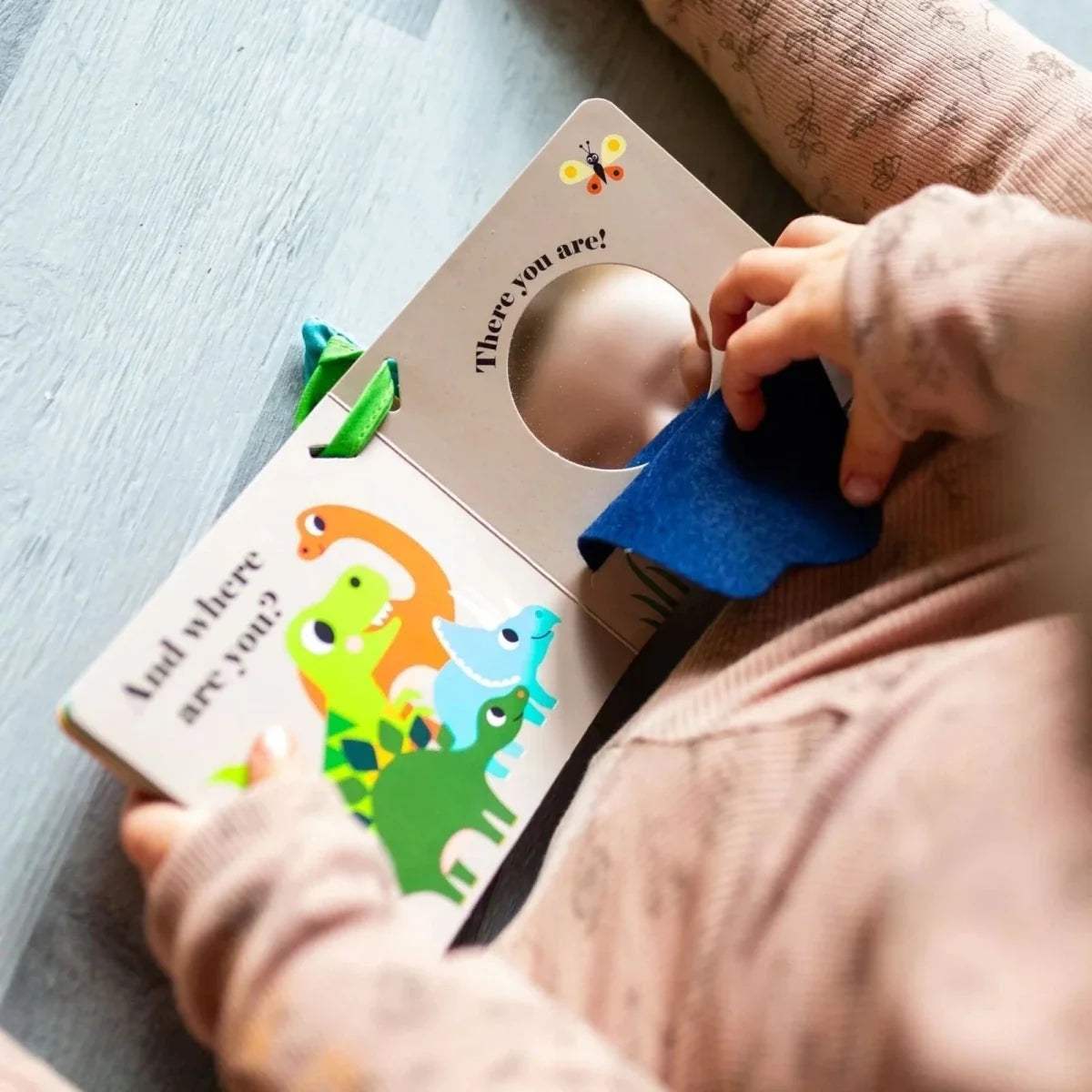 Children's board book page with cutout dinosaur and blue felt flap