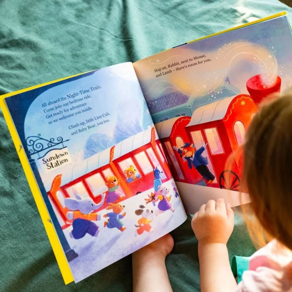 Open children's picture book spread with red train, moon sky, and animal characters