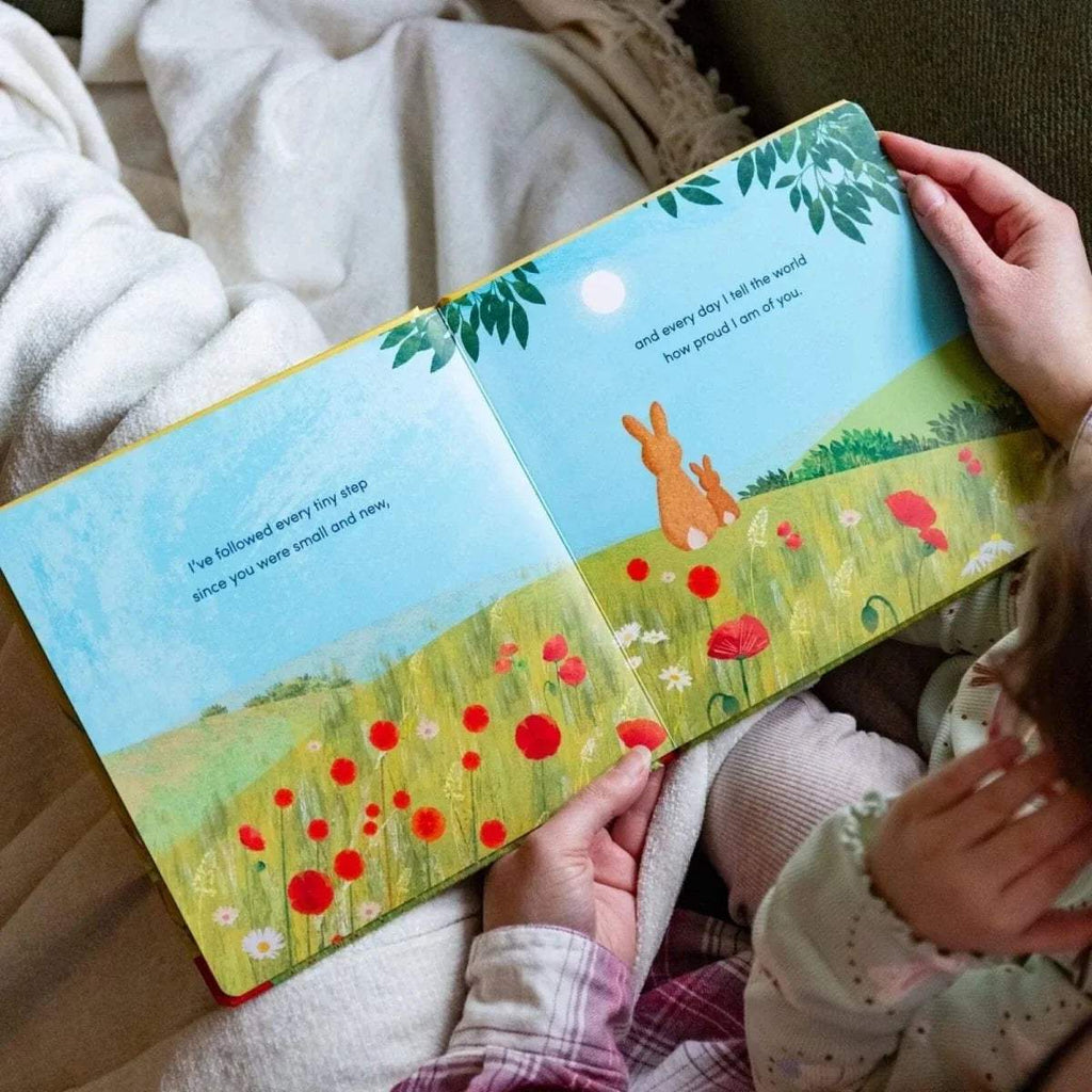 Open children's picture book spread with orange rabbit in a flower field