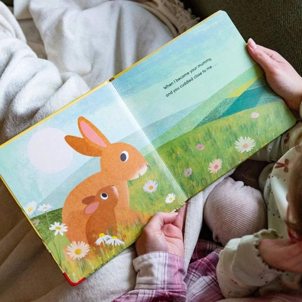 Open children's picture book spread with two orange rabbits in a grassy meadow