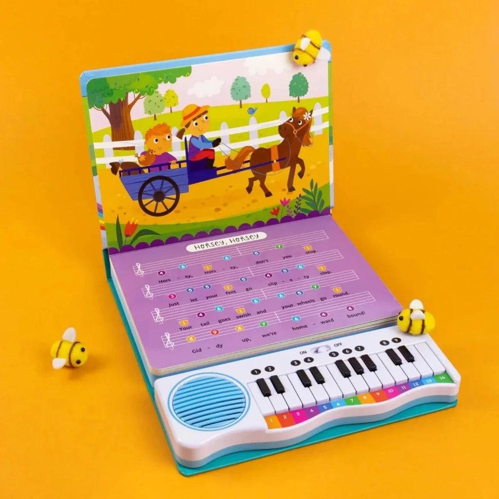 Open musical piano book with colorful note chart, mini keyboard, and speaker