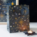 Medium gift bag with dark navy and gold starry print, curved cutout handle