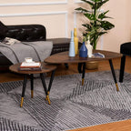 Two walnut round coffee tables with black legs and gold accents beside sofa