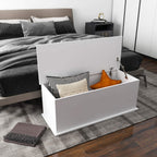 White storage chest with open flip-top lid, holding cushions and folded bedding.
