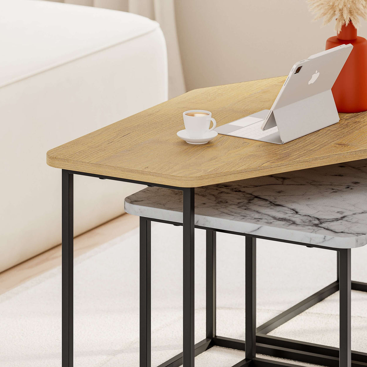 Corner view of a nesting coffee table set: light wood top, black frame, marble shelf