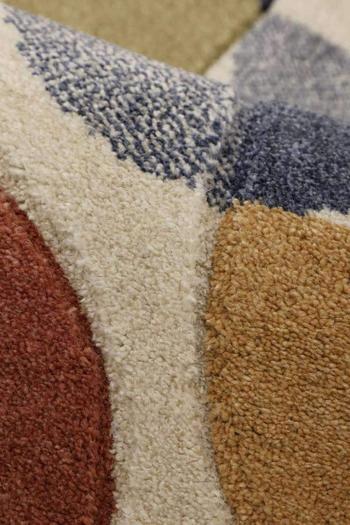 Textured rug close-up with cream pile and navy, rust, and mustard accents