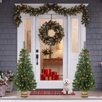 Set of two prelit Christmas trees in pots with green needles, pinecones, berries, warm LED lights