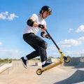 Gold-tone stunt scooter mid-air jump on skatepark ramp