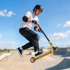 Gold-tone stunt scooter mid-air jump on skatepark ramp