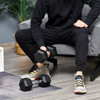 Black hex rubber dumbbells with steel handles being held on a home workout floor