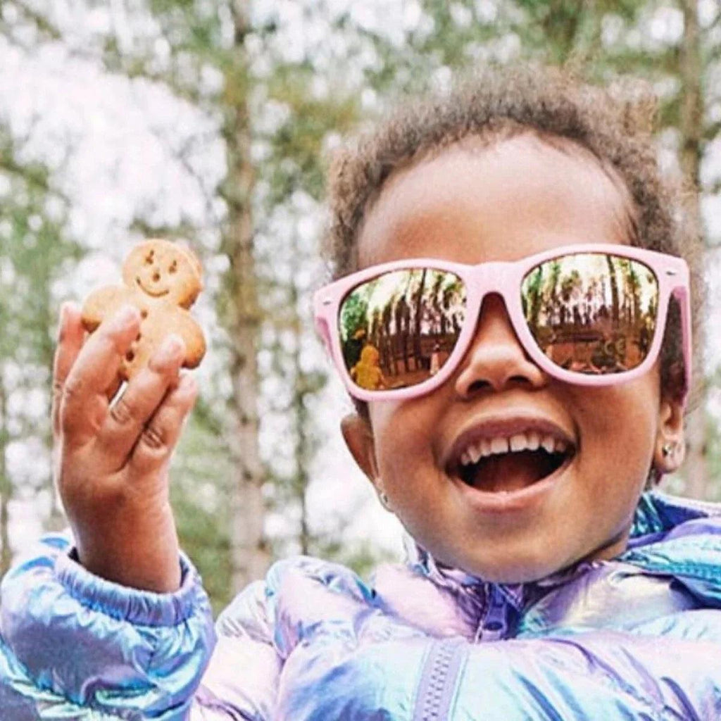 Child holding banana bread biscuit, smiling outdoors