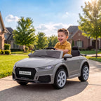 Grey Audi TT RS style 12V ride-on electric car with smiling child seated at front