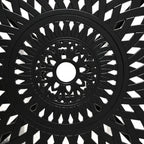 Close-up of black round tabletop with decorative lattice pattern and central hole