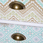 Close-up of patterned drawer fronts with bronze oval handles on a white cabinet