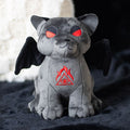 Gray plush toy with red eyes and a symbol on a dark surface