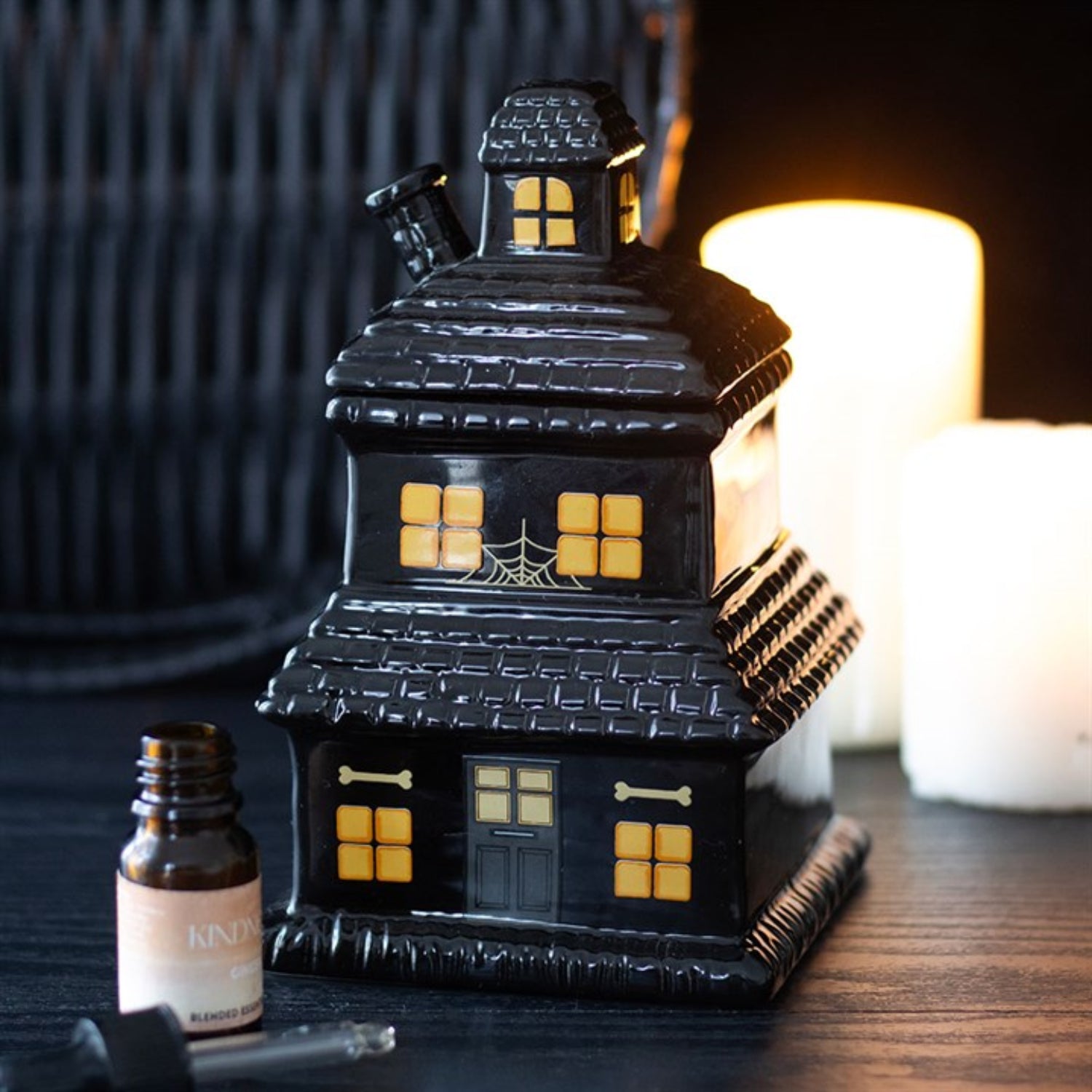 Black haunted house-shaped lantern with glowing windows on a dark surface.