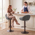 Grey bar stool with padded seat, curved backrest, armrests, and footrest ring