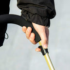 Hand gripping stroller handle while securing the frame on a pink and black pet stroller