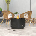 Black square metal fire pit with side vent holes and small flame in outdoor patio